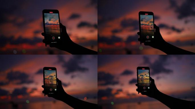 在智能手机上记录日落海滩景观的女性手