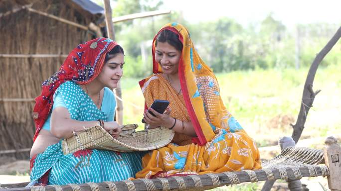 农村妇女在村里清理麦粒和使用电话