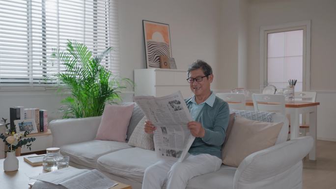老人坐在沙发上看报纸