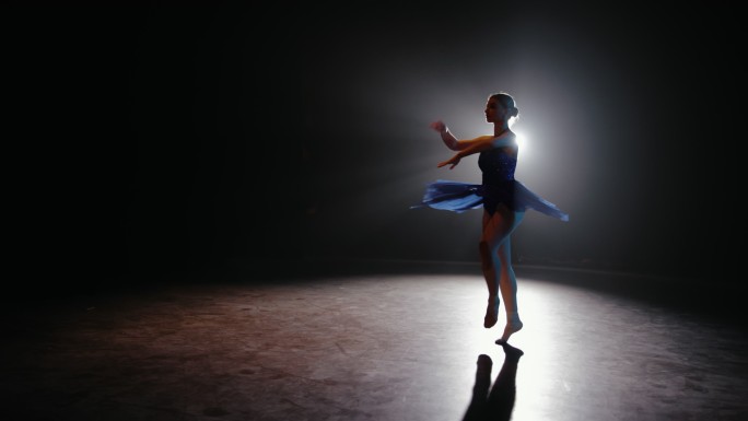 远景：芭蕾舞女演员在舞台上用聚光灯排练她的表演
