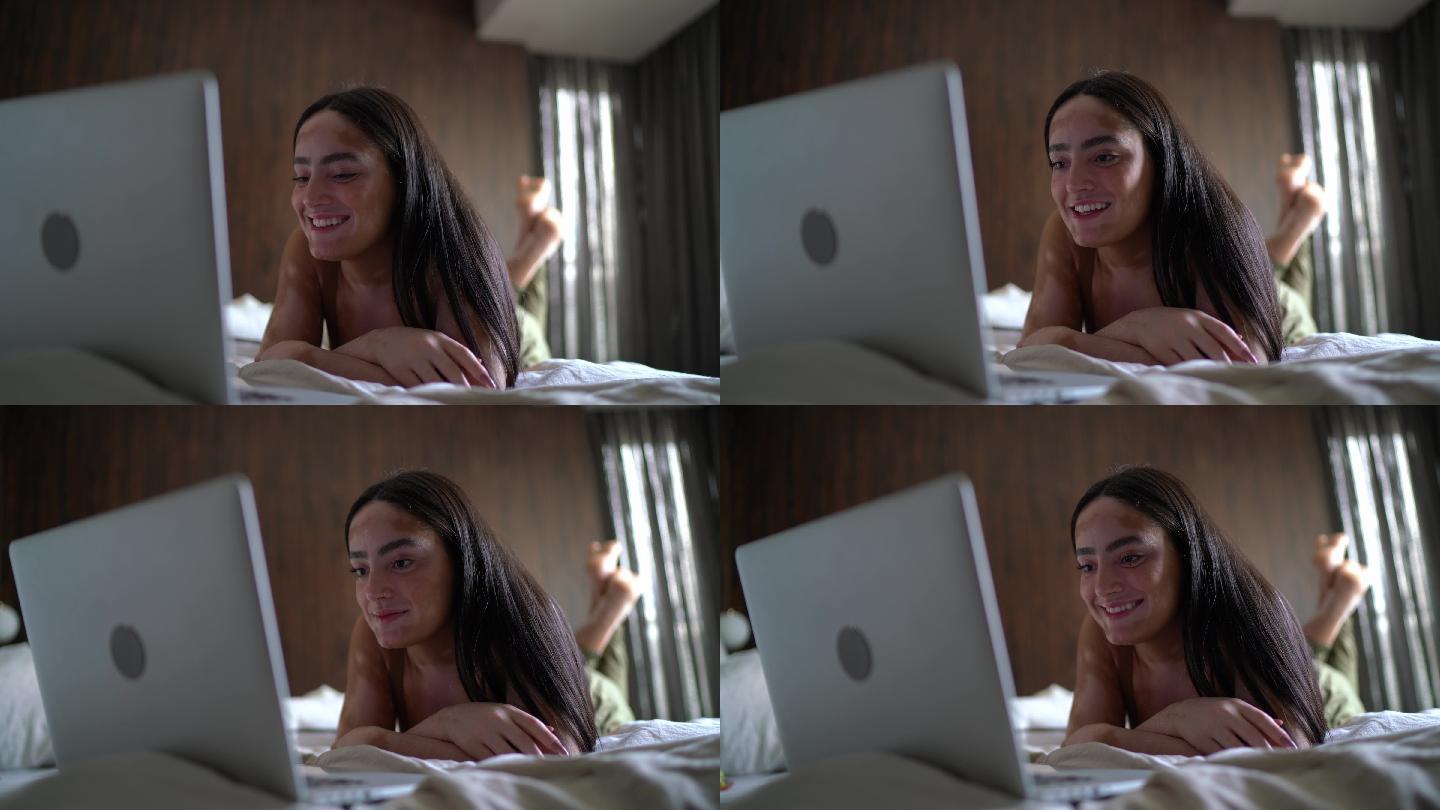 年轻女子在家里的床上看笔记本电脑上的东西