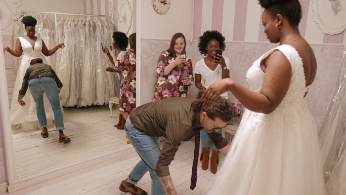 服装设计师在精品店为女性试穿婚纱。
