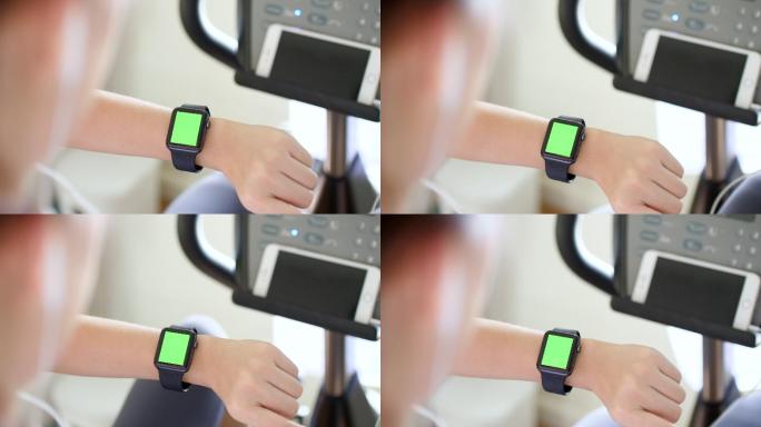 女人们在骑自行车，检查绿色屏幕的智能手表