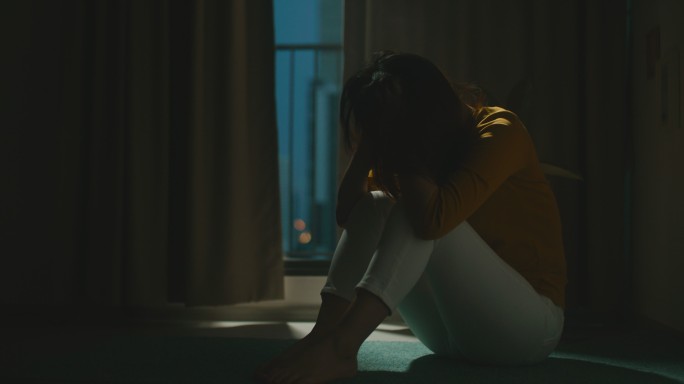沮丧的女人独自坐在公寓房间的地板上