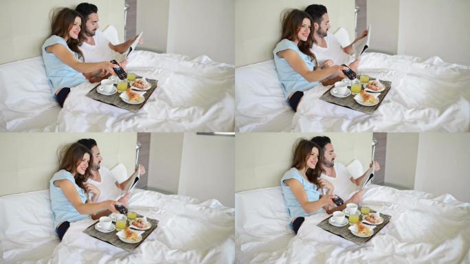 一对夫妇一边看电视一边在床上吃早餐