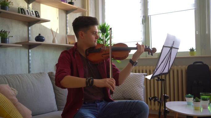 年轻的小提琴手在客厅练习小提琴