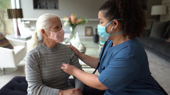 护士在家访时倾听老年患者的心跳——戴上防护口罩