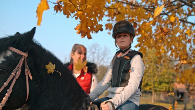 超级斯洛莫母女在秋树下的马背上摆姿势