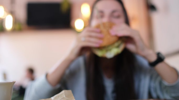 在素食咖啡馆吃素食汉堡的年轻女子