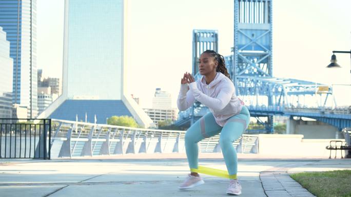 城市滨水区的非裔美国妇女，跳蹲