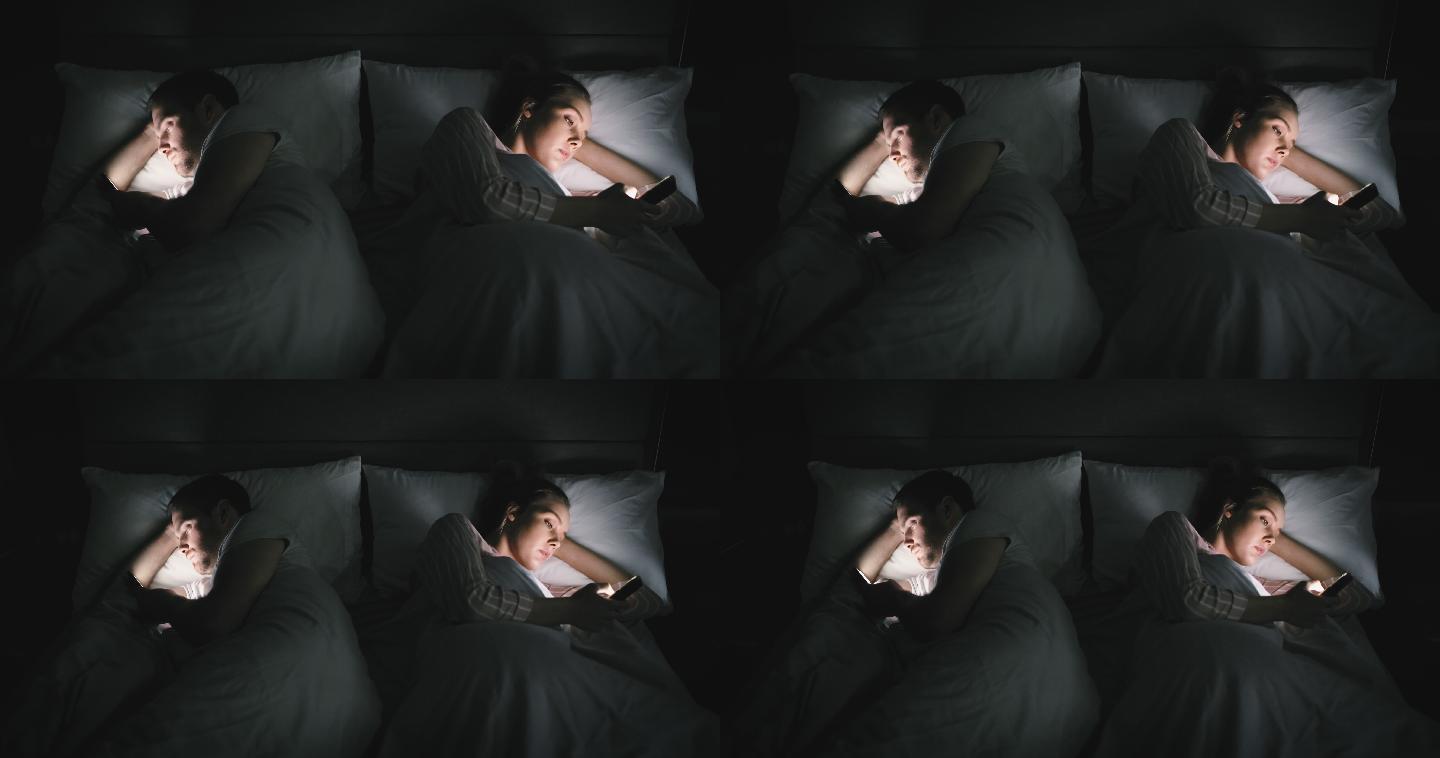 4k视频，一对夫妇在家里使用手机，在床上互相忽视