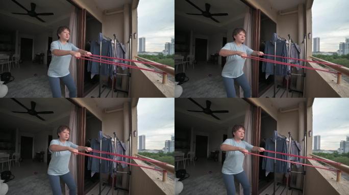 亚裔中国中年女性在阳台上进行阻力带家庭锻炼