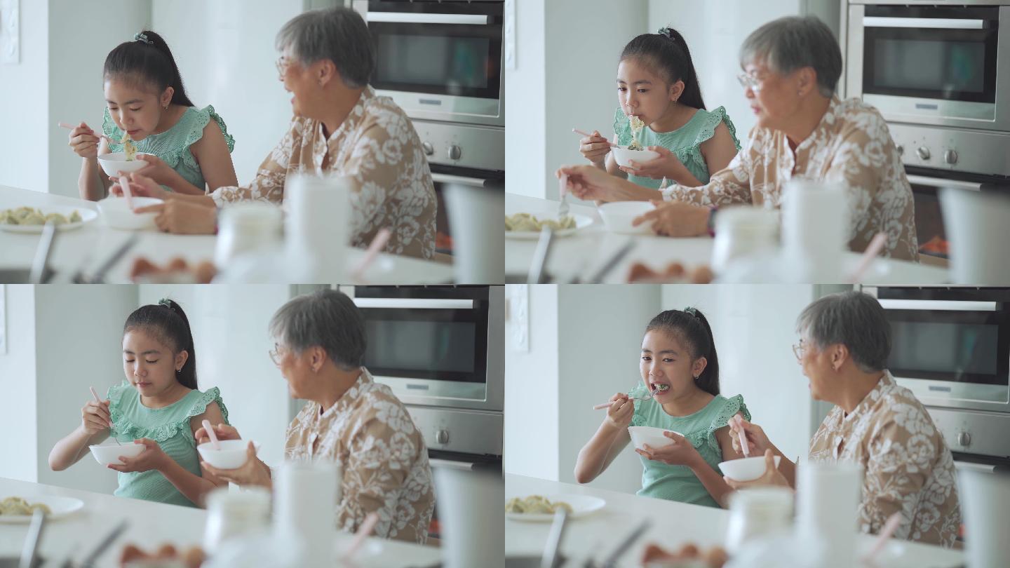 一位亚裔华裔老太太和她的孙女在厨房柜台前吃饺子