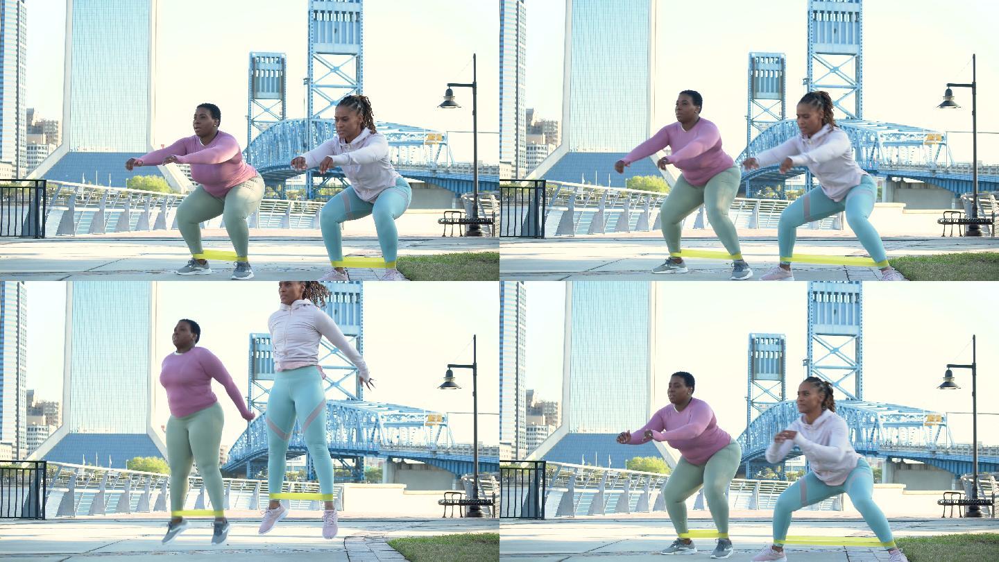两名非裔美国女性在城市公园做蹲跳