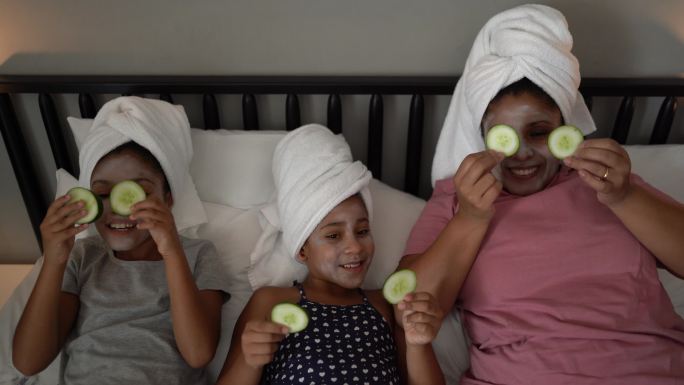 莫瑟和女儿们在床上用黄瓜片敷在眼睛上做皮肤护理