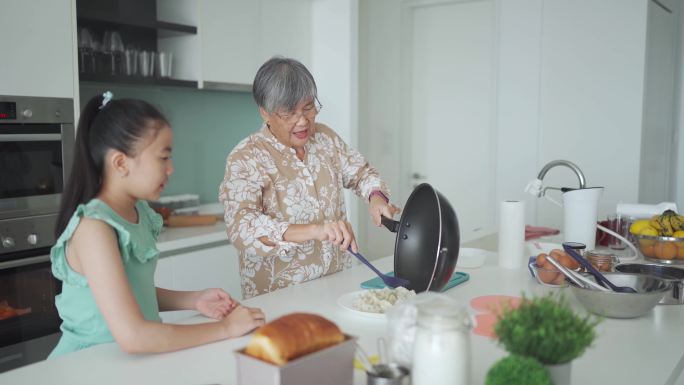 亚裔华裔老太太和她的孙女在周末闲暇时间在厨房准备中国饺子