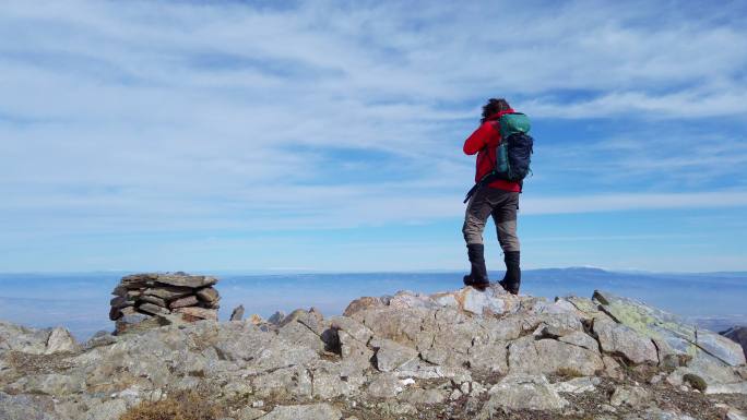 摄影师登山者正在山顶用单反相机拍摄风景