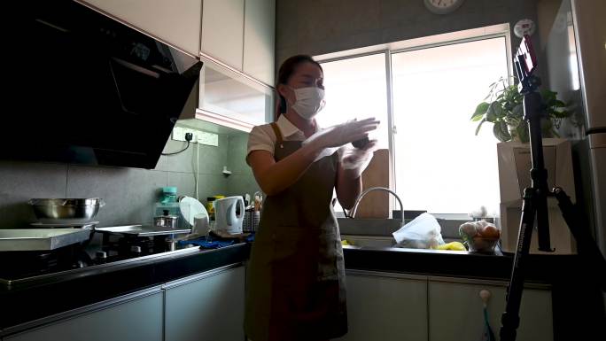一名亚洲女性在现场视频中，在烘焙前在烤盘上为自制的中国月饼面团制作面团