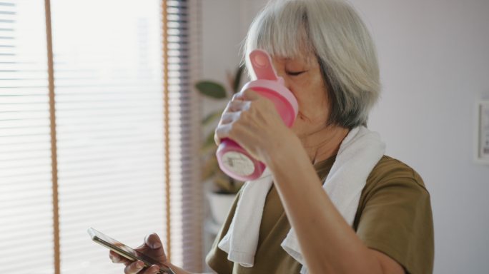 老年女性在锻炼和喝健康饮料后检查心率和卡路里燃烧状态