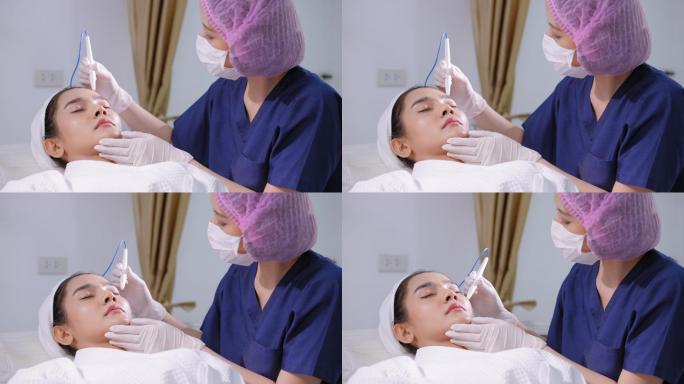 使用特殊设备。美容师对一位亚洲女性的面部进行针刀治疗。戴手套的美容师在美容诊所对患者的前额皮肤进行皮