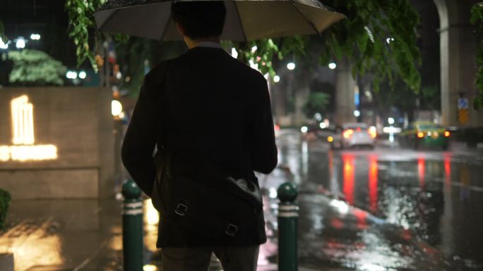 下雨时带着雨伞走路的年轻人
