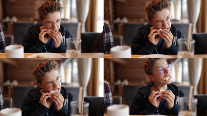 一个十几岁的男孩正在吃一个非常硬的三明治