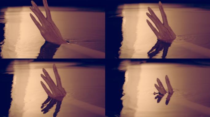 光滑如丝的水面。女性的手轻轻地溅出并接触液体