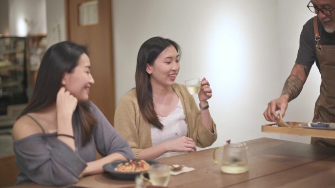 亚裔中国高级服务员在餐厅为女性顾客提供食物