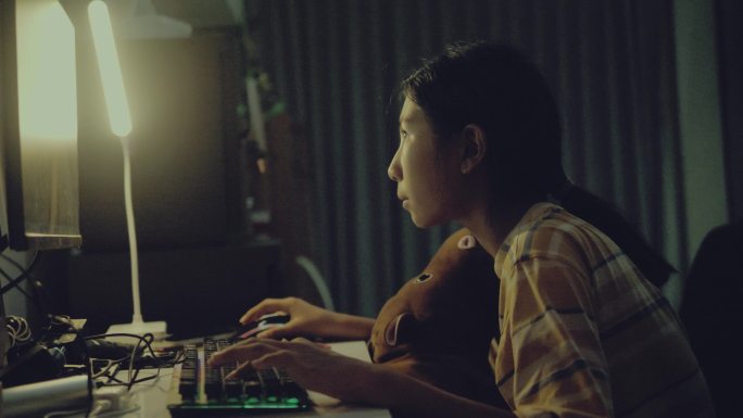 亚洲女孩晚上在家用Pc电脑玩网络游戏，生活方式理念。