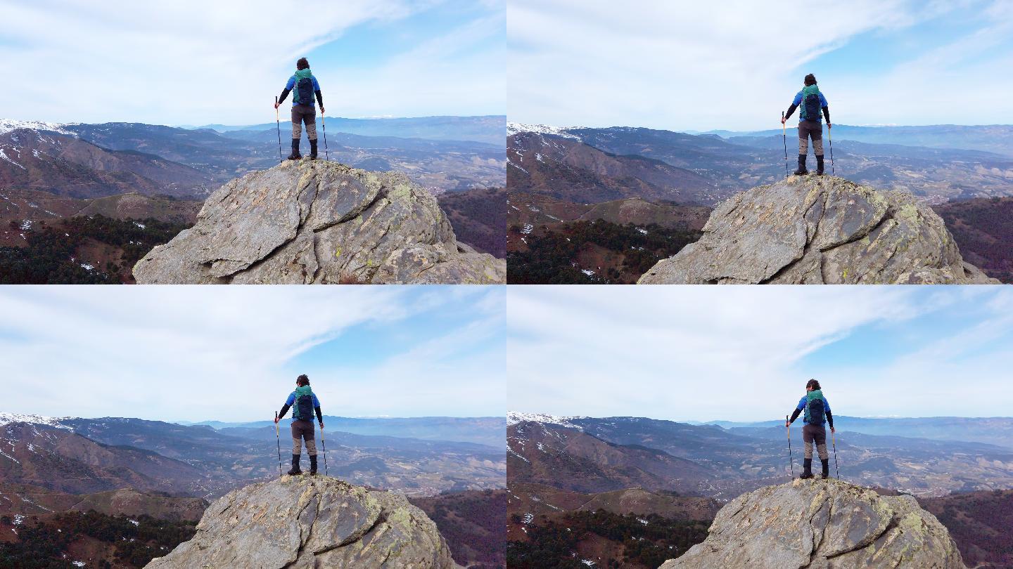 摄影师的后视图登山者手持登山杆在一座落基山的山顶上观看风景。