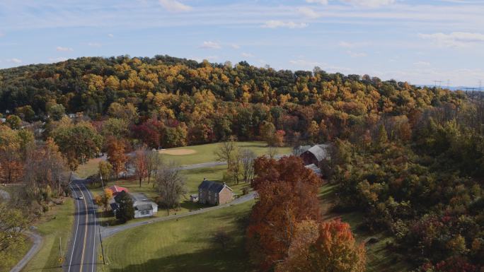 宾夕法尼亚州乡村多彩的秋天。鸟瞰Lehigh镇附近的一个小村庄，在森林覆盖的群山之间。带有平移相机运