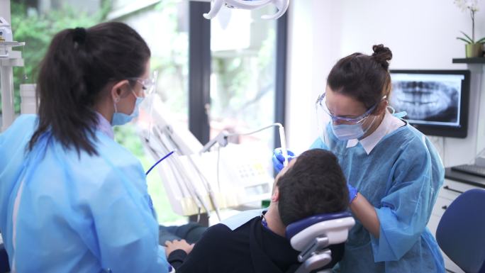 牙医和助理治疗牙科诊所的病人。