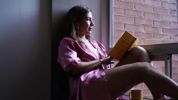 女人在卧室的窗户里看书