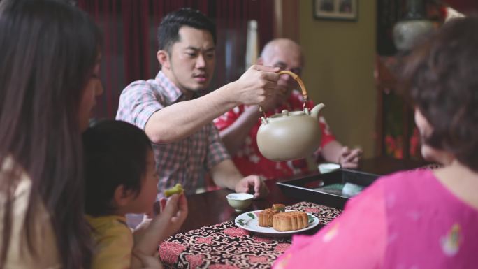 中国的儿子在几代人的时间里喝茶，在下午茶的时候在家里享用传统的中秋月饼和中国茶