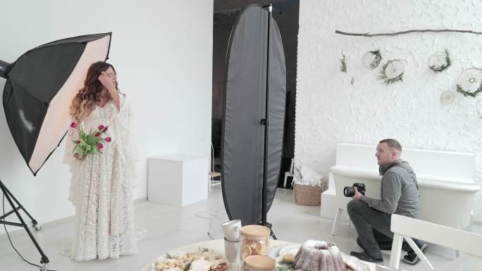 专业摄影师在摄影棚里拍摄怀孕的模特。
