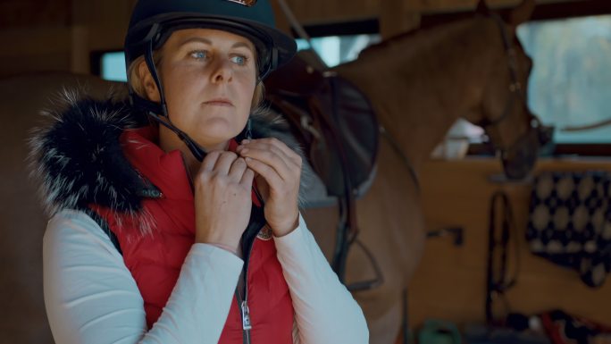 一位女牧场主的斯洛-莫肖像画在骑马前戴上头盔