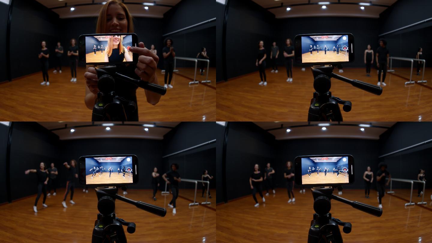 在一所舞蹈学院，美丽的舞蹈老师用三脚架和智能手机与学生们一起录制舞蹈节目