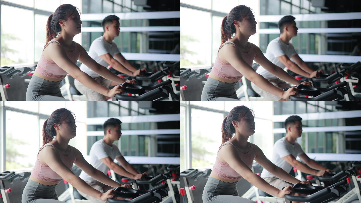 亚洲女子和男子在健身房进行自行车训练