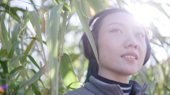 近距离慢动作拍摄一位美丽的亚洲女子在树林中用蓝牙耳机听音乐