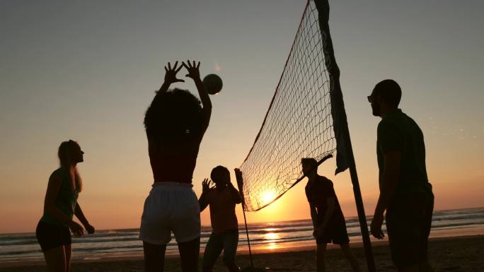 一群年轻人在日落时打沙滩排球