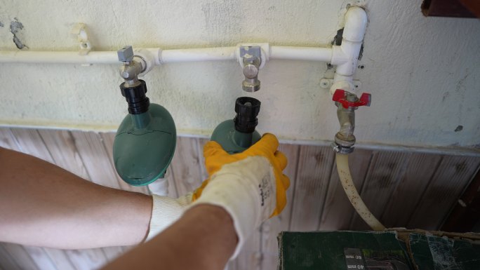 戴着橡胶手套的男性管道工连接粗长管道进行自动灌溉。