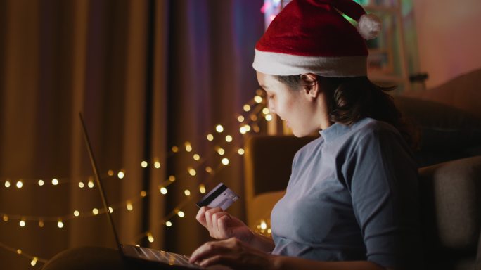 圣诞节，亚洲女性在家里用笔记本电脑在线购物，手持式拍摄