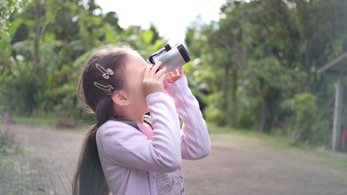 SLO MO可爱快乐的小女孩用双筒望远镜