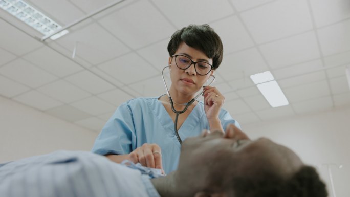 女医生在急诊室用听诊器听心跳。