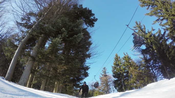 4K滑雪者在滑雪缆车下方的雪坡上跳跃，实时