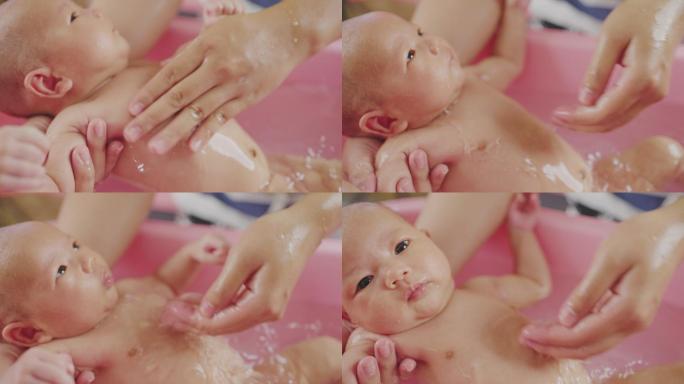 母亲给新生婴儿洗澡，背景是粉红色的。