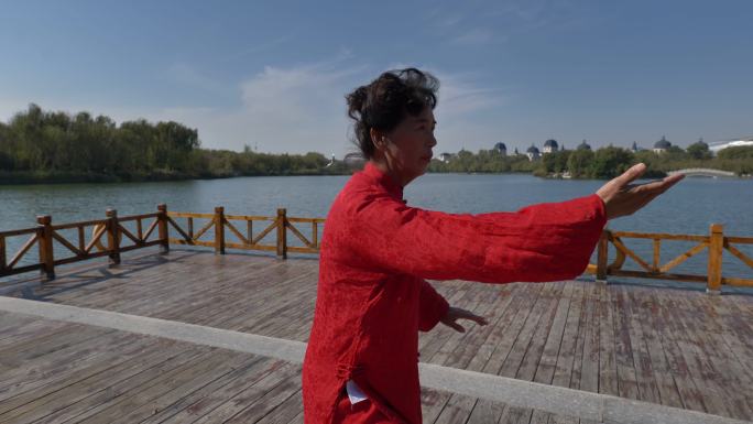 一个女人正在湖边练太极拳。