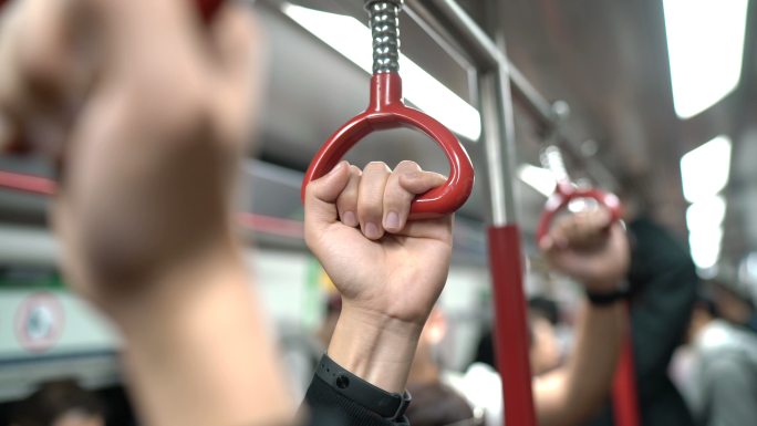在地铁或火车上，三只手握着扶手或扶手带