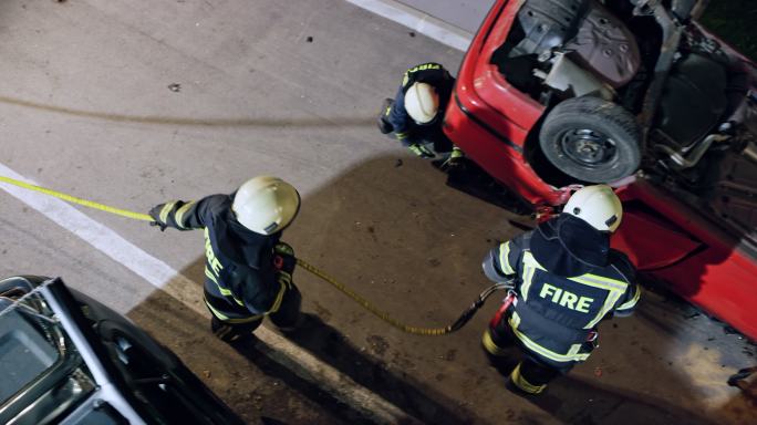 CS消防员在夜间携带液压吊具前往事故现场的失事汽车