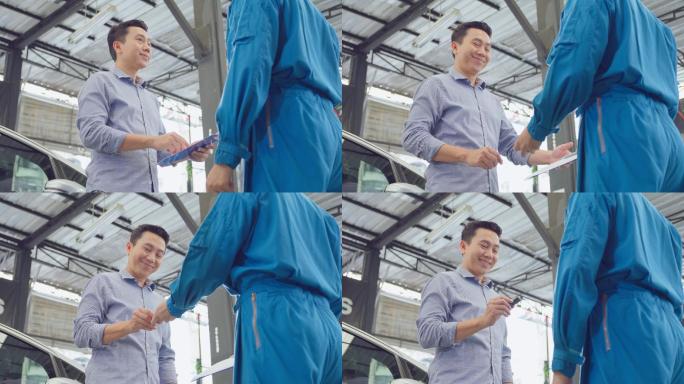 亚洲汽车修理工将汽车遥控钥匙交给客户。汽车维修经理在车库检查和维修汽车发动机成功后，将钥匙交还给车主